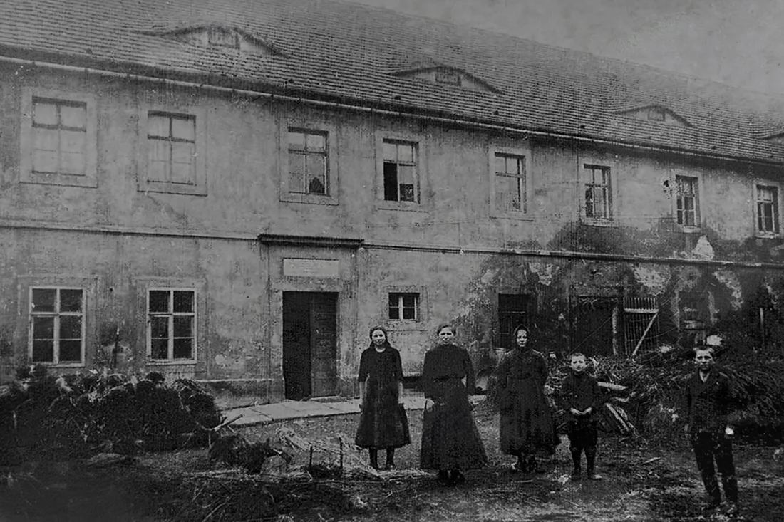 Hofansicht um etwa 1900. Eine Frau steht mit ihren Kindern vor dem alten Hofgebäude in Gohlis.
